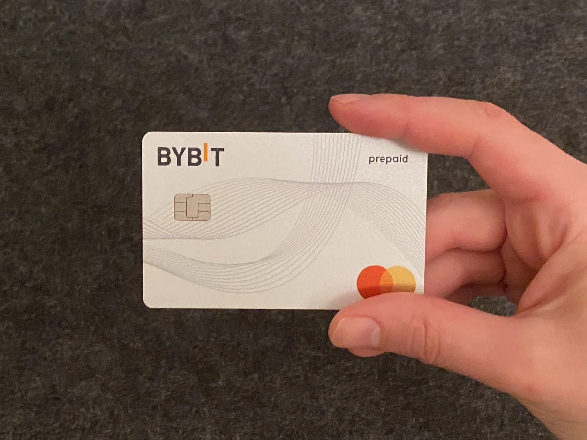 Физическая карта Bybit в руке — белый prepaid Mastercard с чипом, криптокарта биржи Bybit